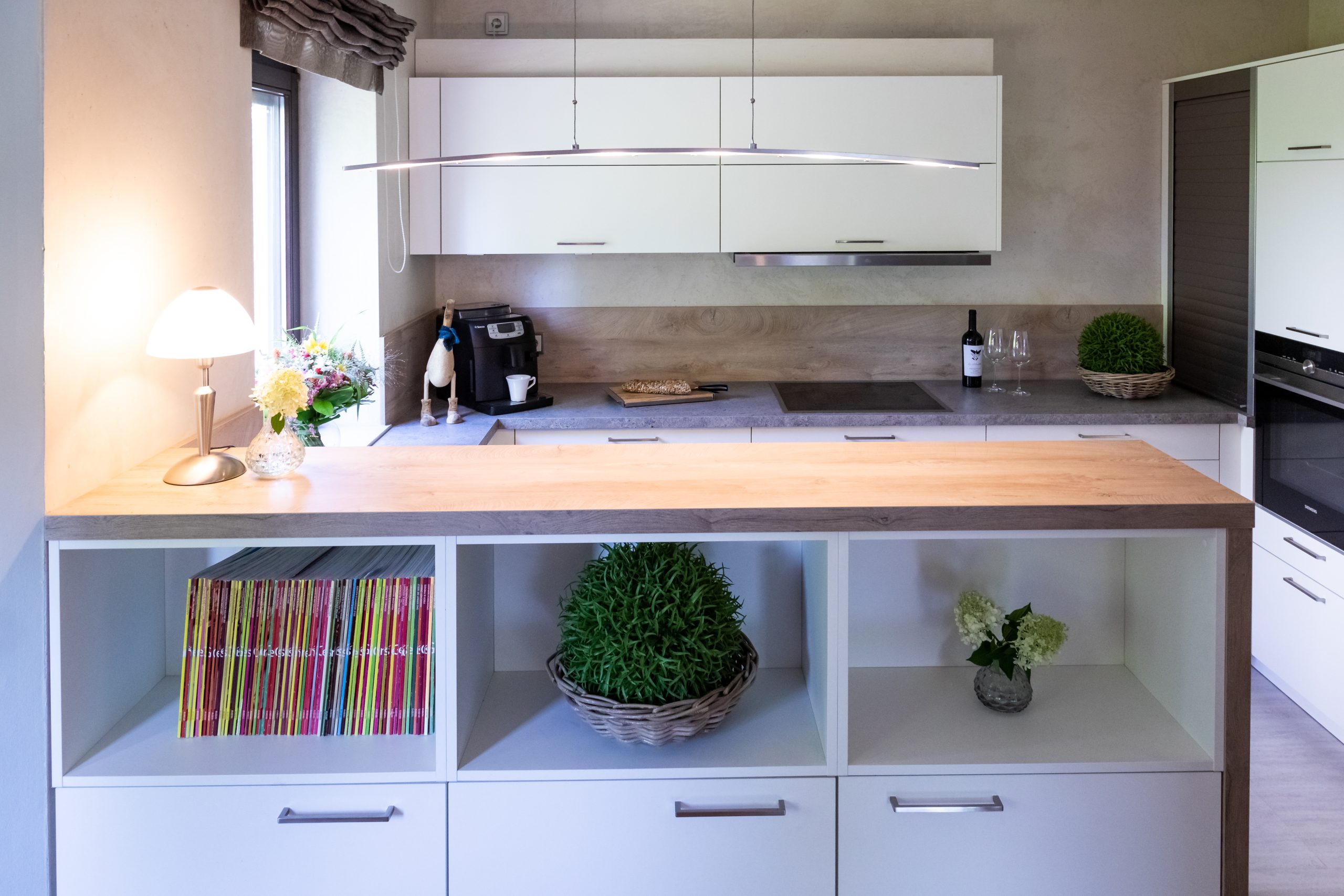 Weiße Küche mit Raumteiler und natürlicher Beleuchtung