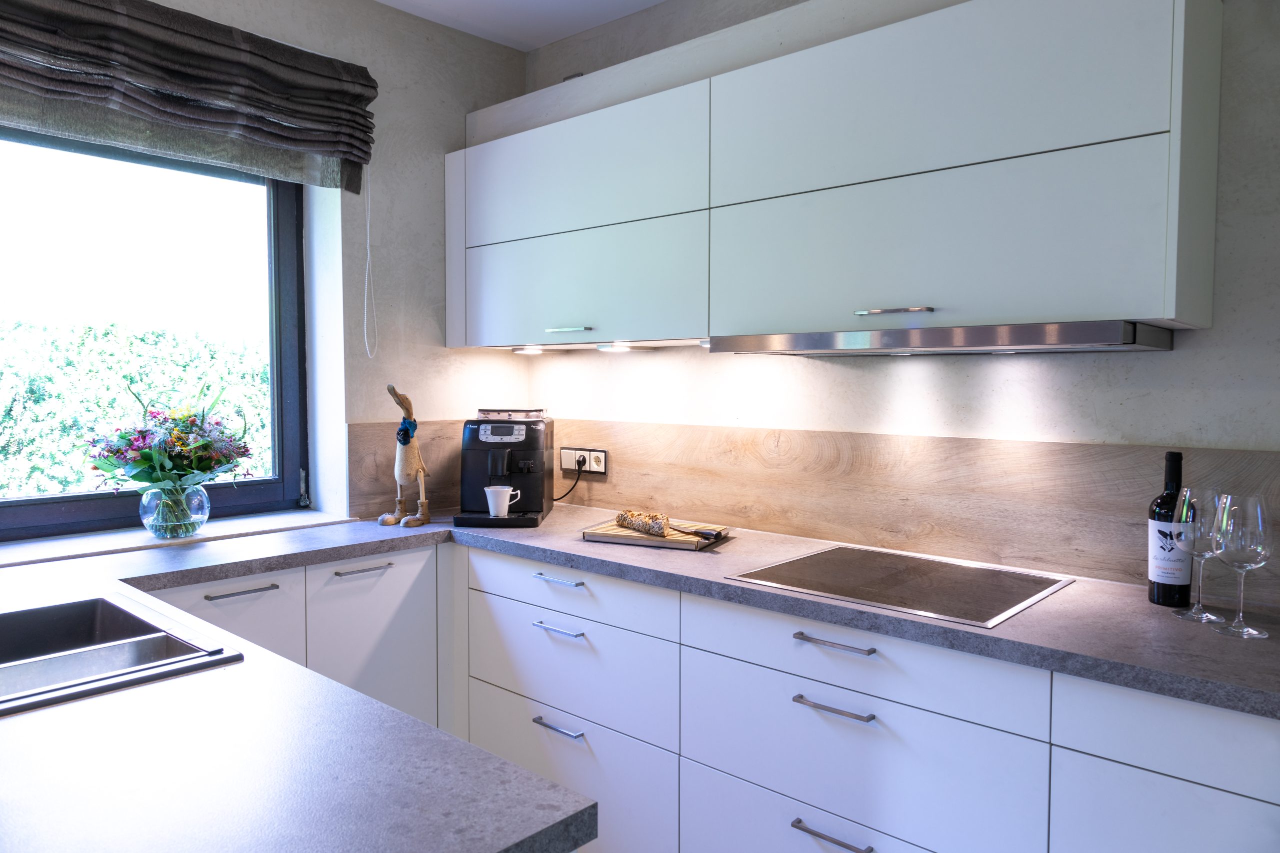 Weiße U-Küche mit Raumteiler und natürlicher Beleuchtung