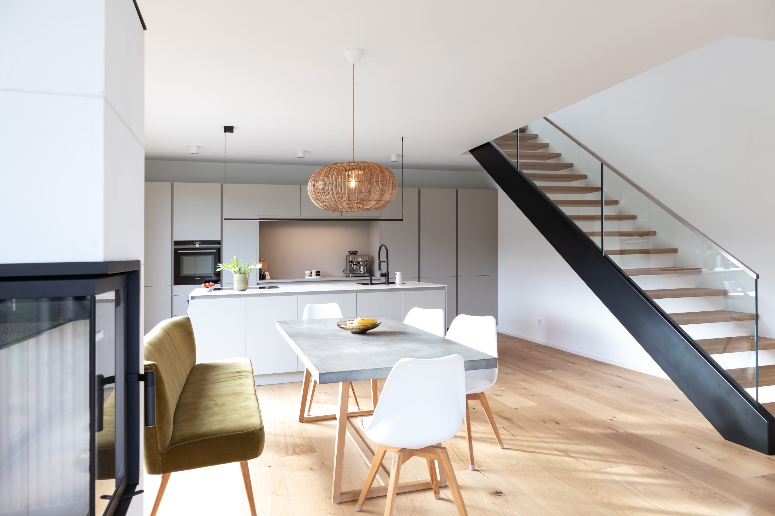 Moderne Designküche mit Kochinsel und freischwebender Holztreppe, Tisch und Sitzbank