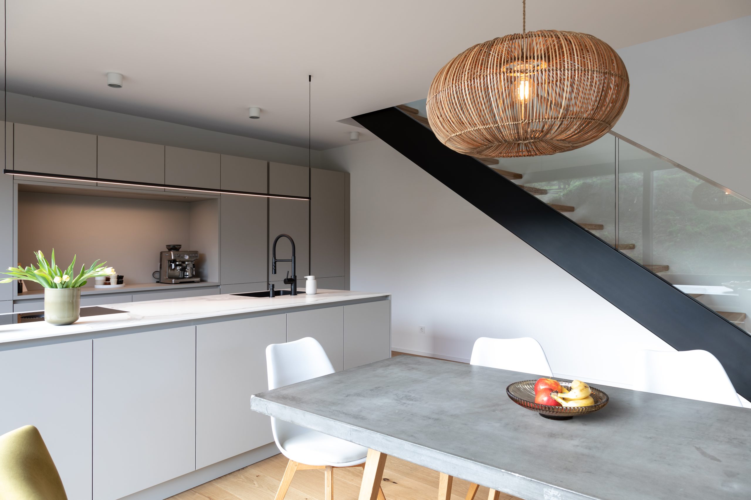 Moderne Designküche mit Tisch Kochinsel und freischwebender Holztreppe