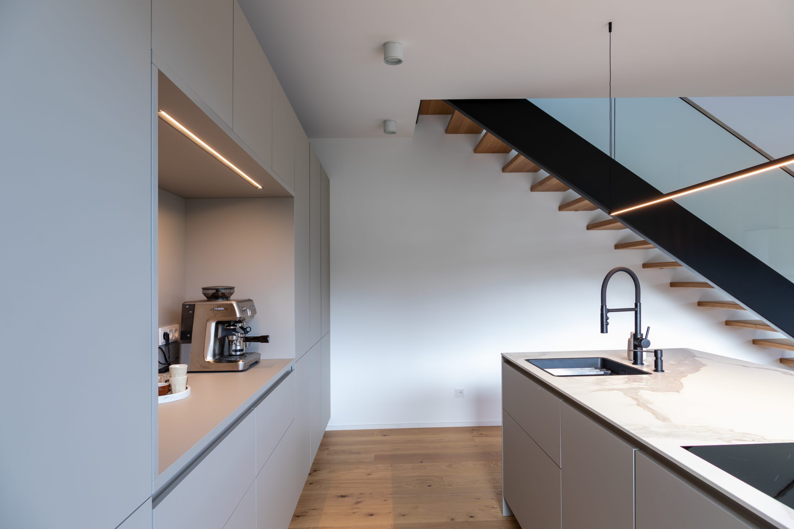 Moderne Designküche mit Kochinsel und freischwebender Holztreppe