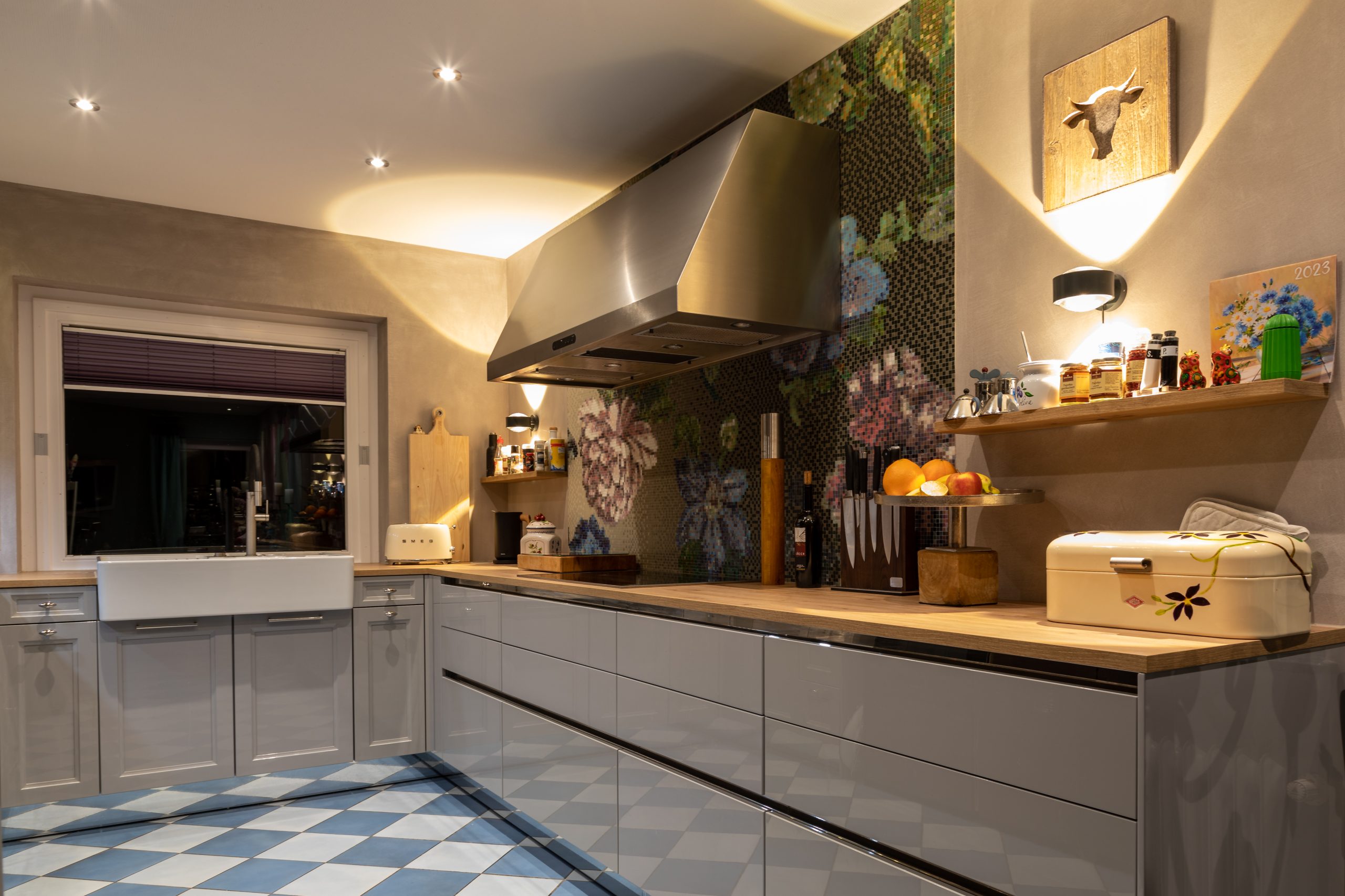 Gemütliche Küche mit Blumenmosaik, Landhausspüle und stimmungsvoller Beleuchtung