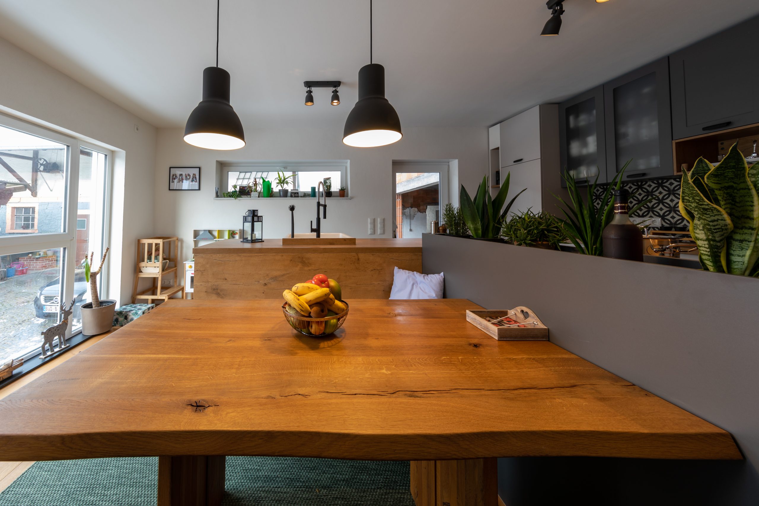 Wohnküche mit Massivholztisch, Hängelampen und vielen Zimmerpflanzen