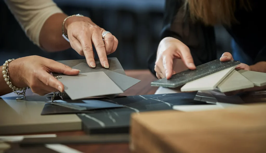 Ein Ausschnitt aus einem Beratungsgespräch: Zu sehen sind zwei Hände, die verschiedene Materialproben begutachten und besprechen – ein Beispielbild für Küchenplaner Hanau.